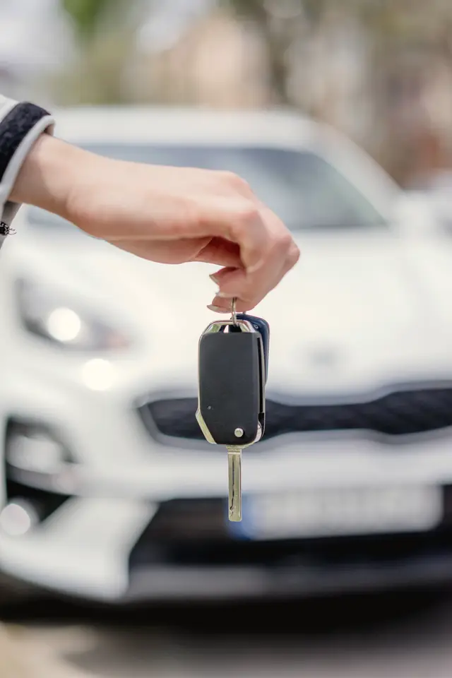 Clé de voiture tendue devant un véhicule blanc